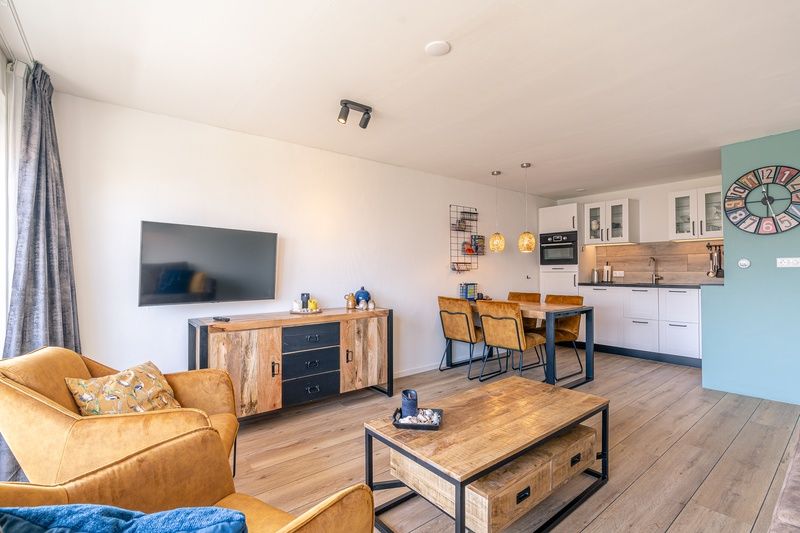 Eetkamer en keuken in Appartement Anna 220, De Koog, Texel met houten eettafel en stijlvolle verlichting.