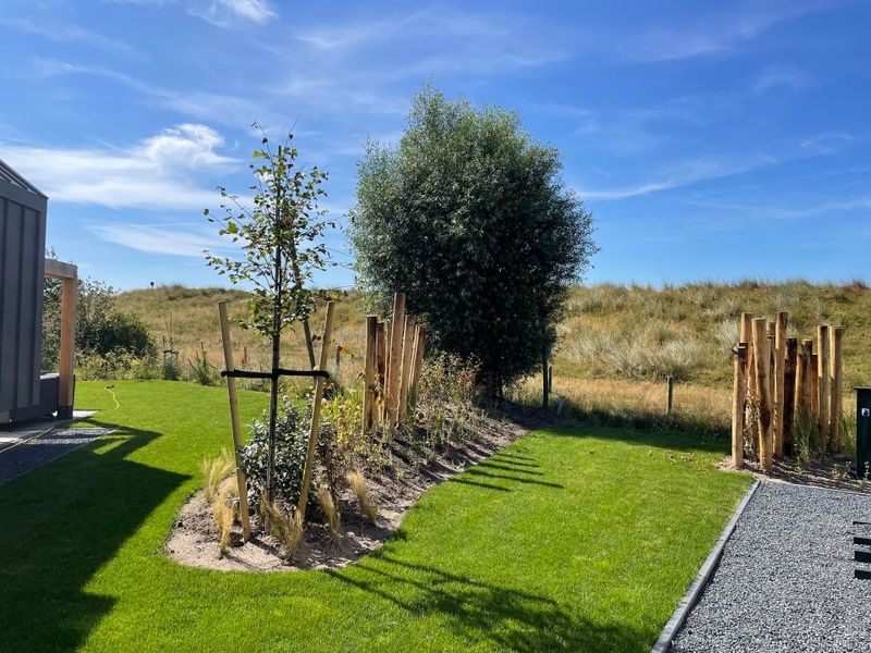 Natuurlijke omgeving van Duinvilla Wellness 5 in De Koog, Texel, met uitzicht op duinen en groene tuin.