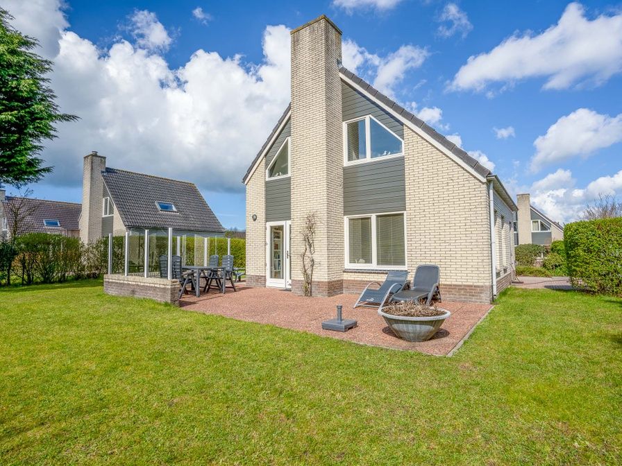 Aussenbereich des Ferienhauses Honeysuckle 91 mit Sauna, De Koog, Texel, mit sonniger Terrasse und gruenem Garten.