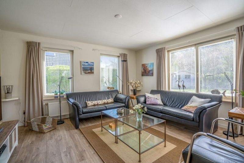 Gemuetliches Wohnzimmer im Ferienhaus Kamperfoelie 91, De Koog, Texel, mit bequemen Sofas und viel Licht.