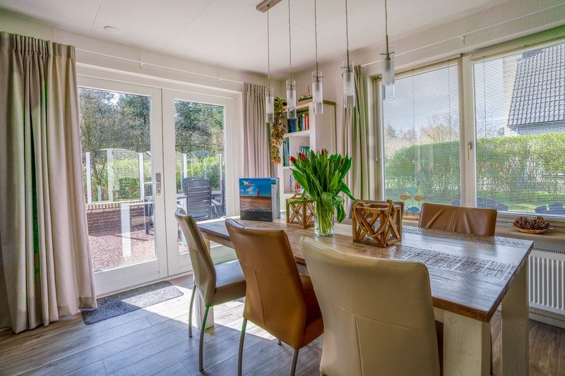 Essecke im Ferienhaus Honeysuckle 91, De Koog, Texel, mit Blick auf den Garten und Zugang zur Terrasse.