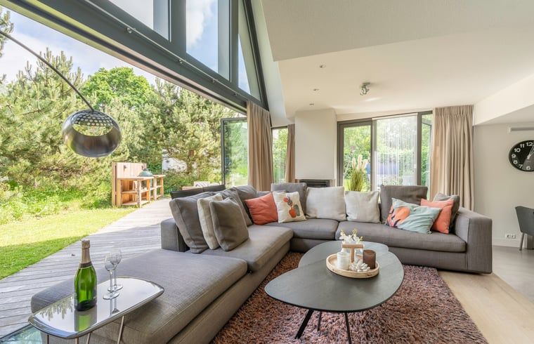 Gemuetliches Wohnzimmer im Ferienhaus in De Koog, Texel, mit grossen Fenstern und Blick auf die Natur, perfekt fuer Entspannung auf den Watteninseln.