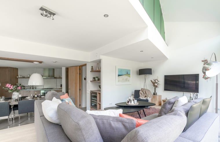 Der offene Wohnbereich im Ferienhaus in De Koog, Texel, mit Blick auf die Kueche und den Essbereich, bietet eine gemuetliche Atmosphaere auf den Watteninseln.