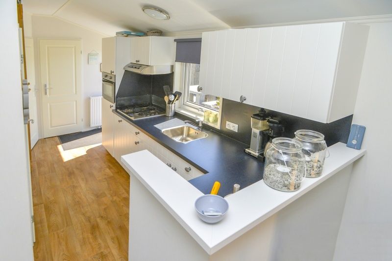 Moderne keuken in Chalet Bregkoog 215 Zandhuisjes op Chaletpark Bregkoog, De Koog, Texel met strakke werkbladen en veel licht.