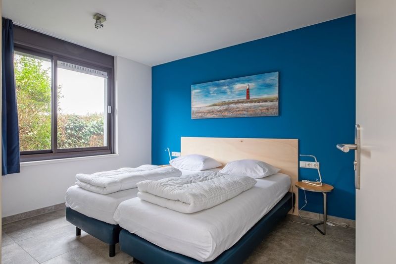 Slaapkamer in Orchismient 20 vakantiehuis De Koog Texel met tweepersoonsbed en blauwe muur.