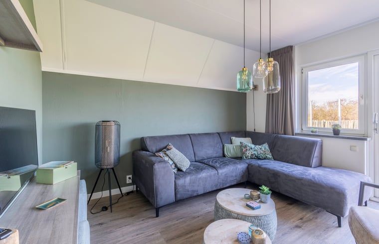 Modern living room in Holiday home in De Waal, Texel with comfortable corner sofa and views of nature.