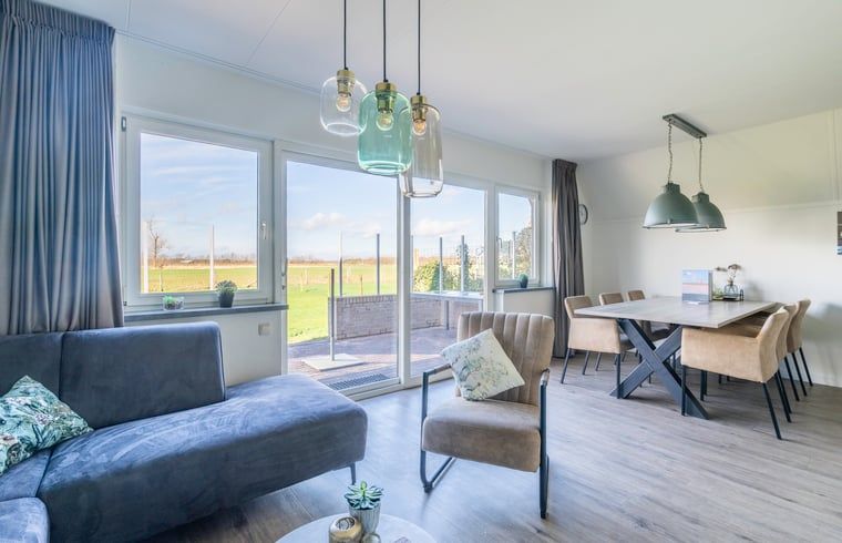 Bright living room in Holiday Home in De Waal, Texel with large windows and views of the terrace.
