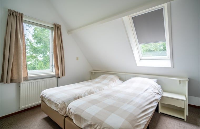 Slaapkamer in Huisje in De Waal, Texel met twee eenpersoonsbedden en serene uitzichten.