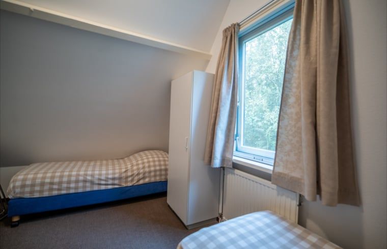 Gezellige slaapkamer met eenpersoonsbedden in Huisje in De Waal, Texel, ideaal voor kinderen.