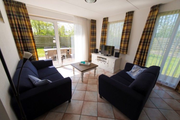 Gemtliches Wohnzimmer im Ferienhaus De Boogerd, De Waal, Texel mit Blick auf den grnen Garten, ideal fr Familientreffen.