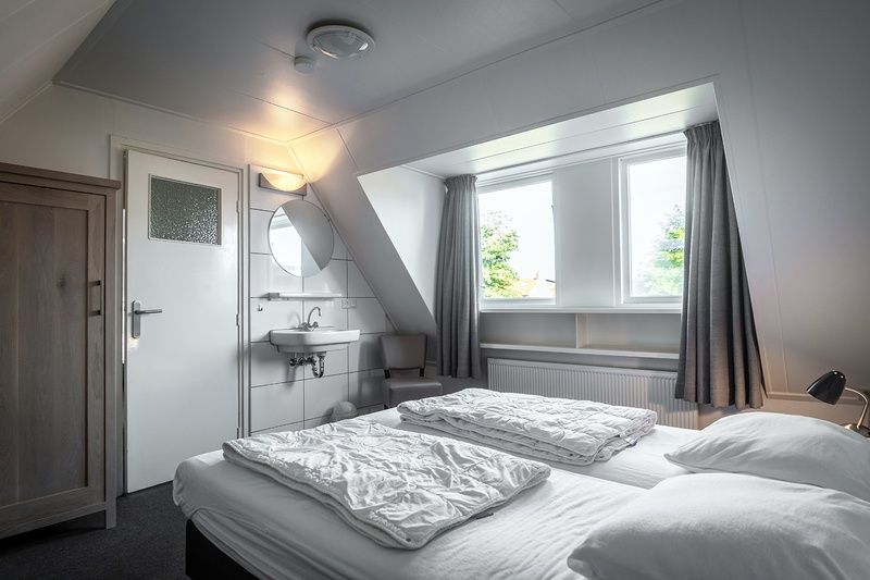Bright bedroom in Holiday home De Heggemus, Den Burg, Texel with large window and modern furniture.