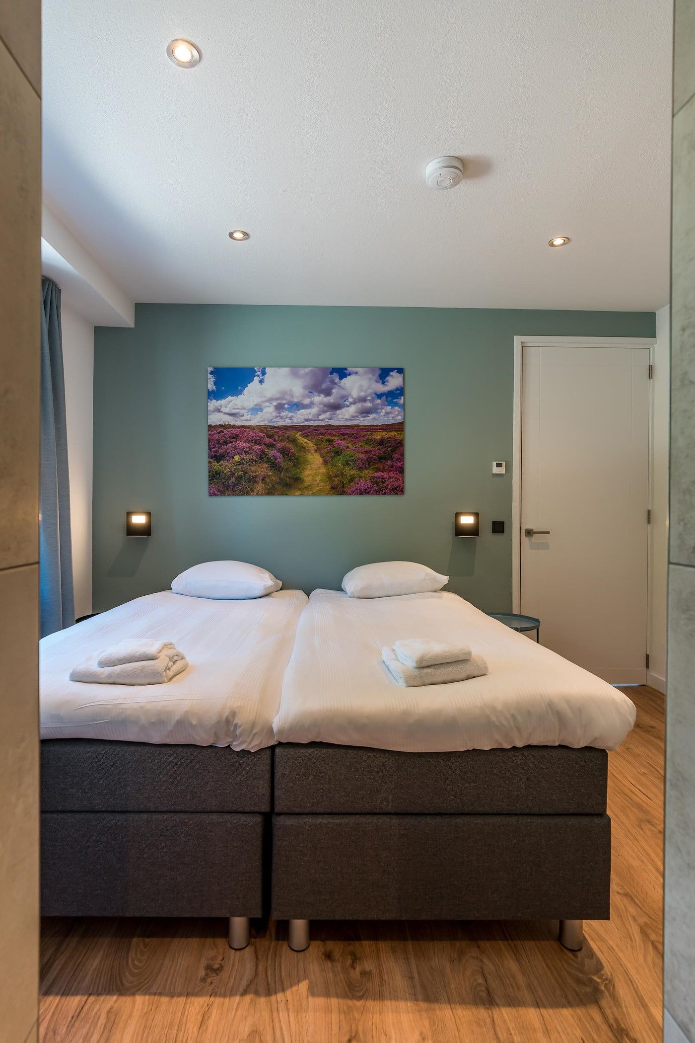 Slaapkamer in Blauwe Kiekendief vakantiehuis Den Burg Texel met tweepersoonsbed en kunst.