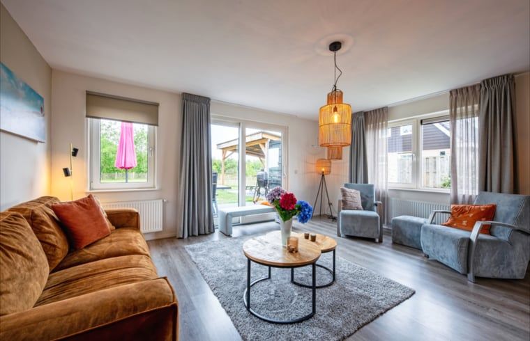 Gezellige woonkamer van Vakantiehuisje in Den Burg, Texel met comfortabele zithoek en uitzicht op de tuin, ideaal voor ontspanning.