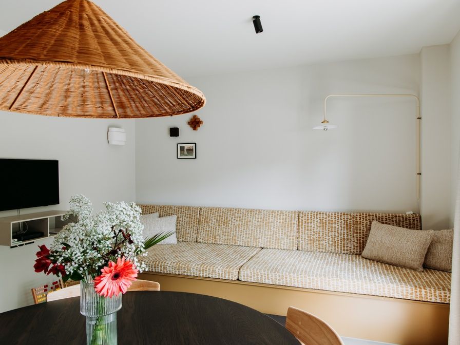 Gemuetliche Sitzecke im Luxury Apartment 4p, Den Burg, Texel mit stilvoller Rattanlampe und frischen Blumen.