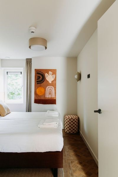 Rustgevende slaapkamer in Wellness Appartement 6p, Den Burg, Texel met natuurlijk licht en artistieke decoratie.