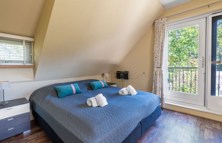 Tweede slaapkamer in Huisje in Den Burg, Texel met balkon en uitzicht op de tuin.