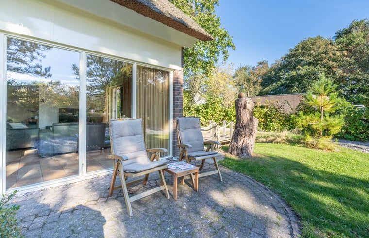 Zonnige zithoek buiten Huisje in Den Burg, Texel met comfortabele stoelen.