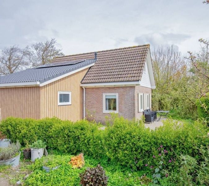 Seitenansicht des Ferienhauses 5 Persoons in Den Burg Texel, mit gruenem Garten auf den Watteninseln.