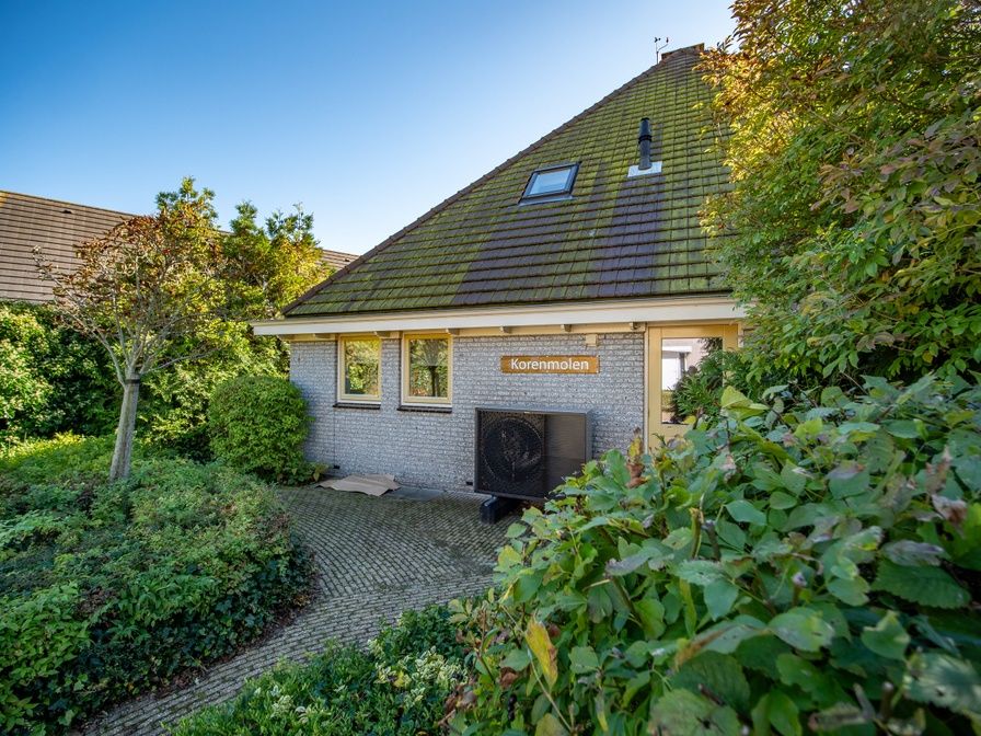 Korenmolen vakantiehuis in Den Burg, Texel omgeven door groene natuur.