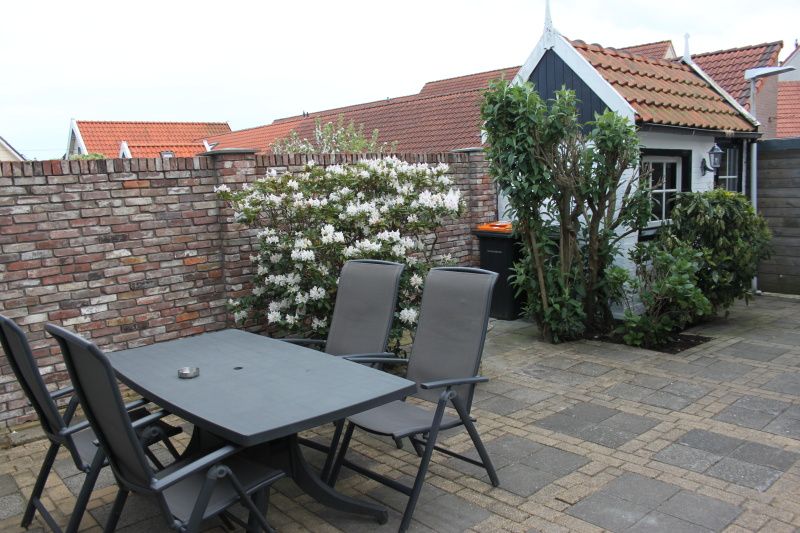 Spacious terrace at De Molen, vacation home in Den Burg, Texel, with garden furniture and flowers.