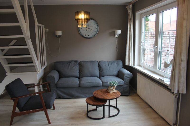Stylish living room with sofa and clock in vacation home De Molen, Den Burg, Texel.