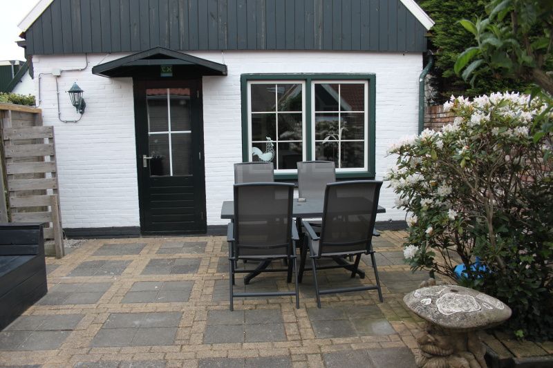 Sunny terrace with dining table at De Molen, vacation home in Den Burg, Texel.
