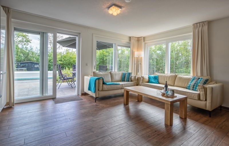 Lichte woonkamer in Villa 3C, Den Burg Texel, vakantiehuis met uitzicht op terras en natuur.