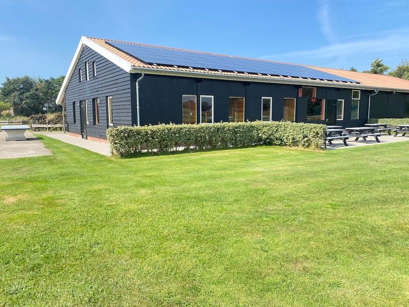 Sonniger Aussenbereich von De Stolp II rechts, Ferienhaus in Den Hoorn, Texel mit gruenem Garten.