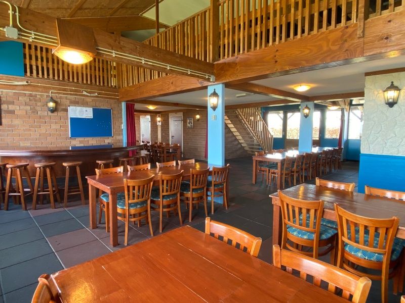 Geraeumiges Esszimmer in De Stolp II rechts, Ferienhaus in Den Hoorn, Texel mit Holztischen und Stuehlen.