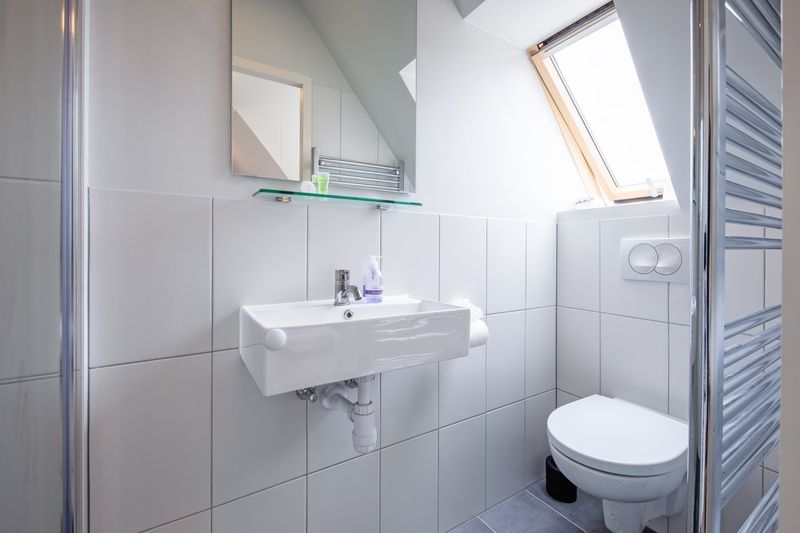 Modernes Badezimmer mit Waschbecken und Toilette im Hotel Loodsmans Welvaren - Apartment, Den Hoorn, Texel.