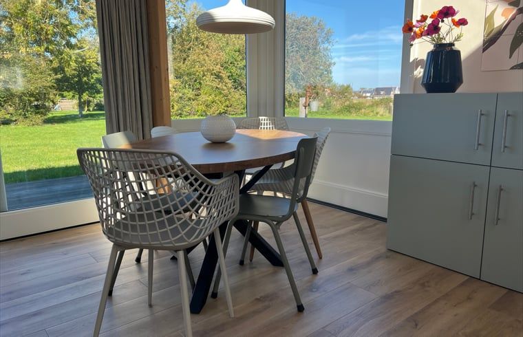 Essecke im Ferienhaus in Den Hoorn, Texel, mit Blick auf die gruene Landschaft.