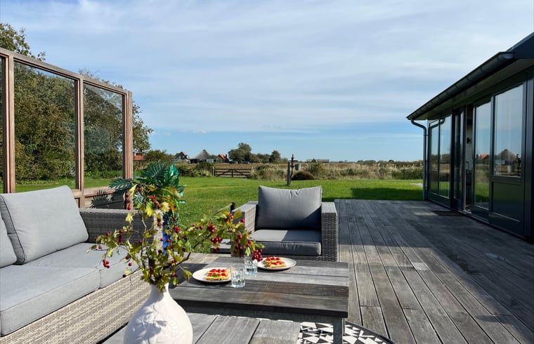 Aussenterrasse mit Sitzgelegenheiten und Blick auf Texel im Ferienhaus in Den Hoorn.