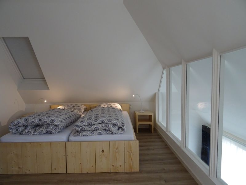 Gemuetliches Mansardenzimmer im Ferienhaus De Dors Den Hoorn Texel mit Dachfenster und Holzbett.