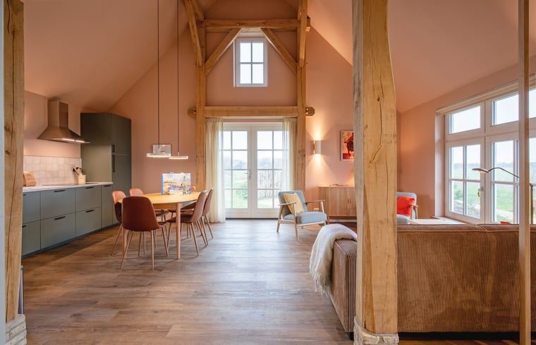 Gezellige woonkamer in het Huisje in Den Hoorn, Texel met houten balken en veel lichtinval, ideaal vakantiehuis op de Waddeneilanden.