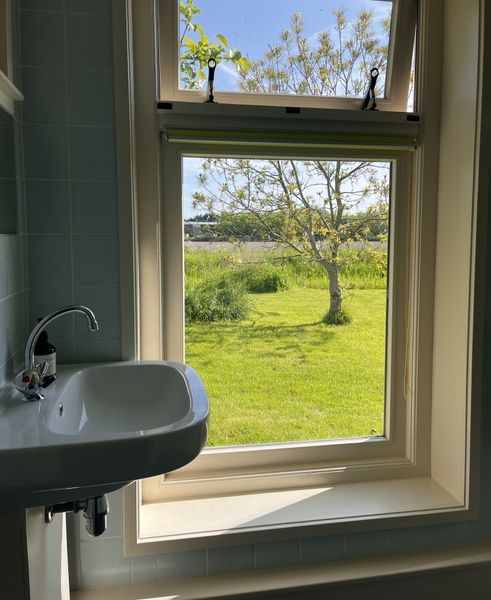 Blick aus dem Badezimmerfenster des Ferienhauses De Viersprong in Oosterend, Texel, ueber gruene Felder.