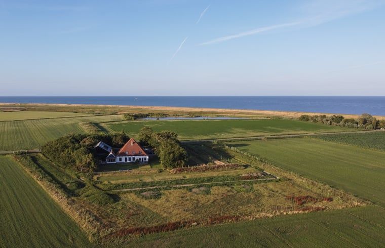 Holzschild mit der Aufschrift "Gaestehaus" an einem Ferienhaus in Oosterend, Texel, umgeben von Gruenanlagen.