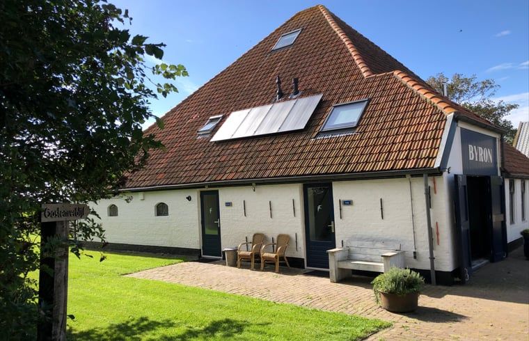 Gemuetlicher Innenbereich des Ferienhauses in Oosterend, Texel, mit Essbereich und offener Treppe.