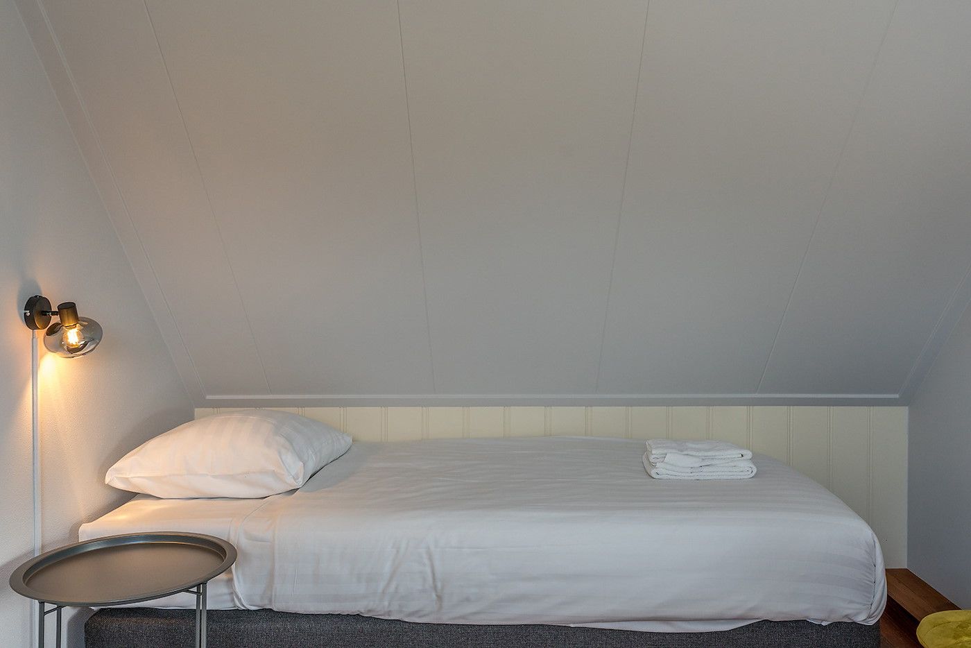 Eenpersoonsbed in Gouden Rijder vakantiehuis, Oosterend, Texel, met nachtlampje en opgemaakt bed.