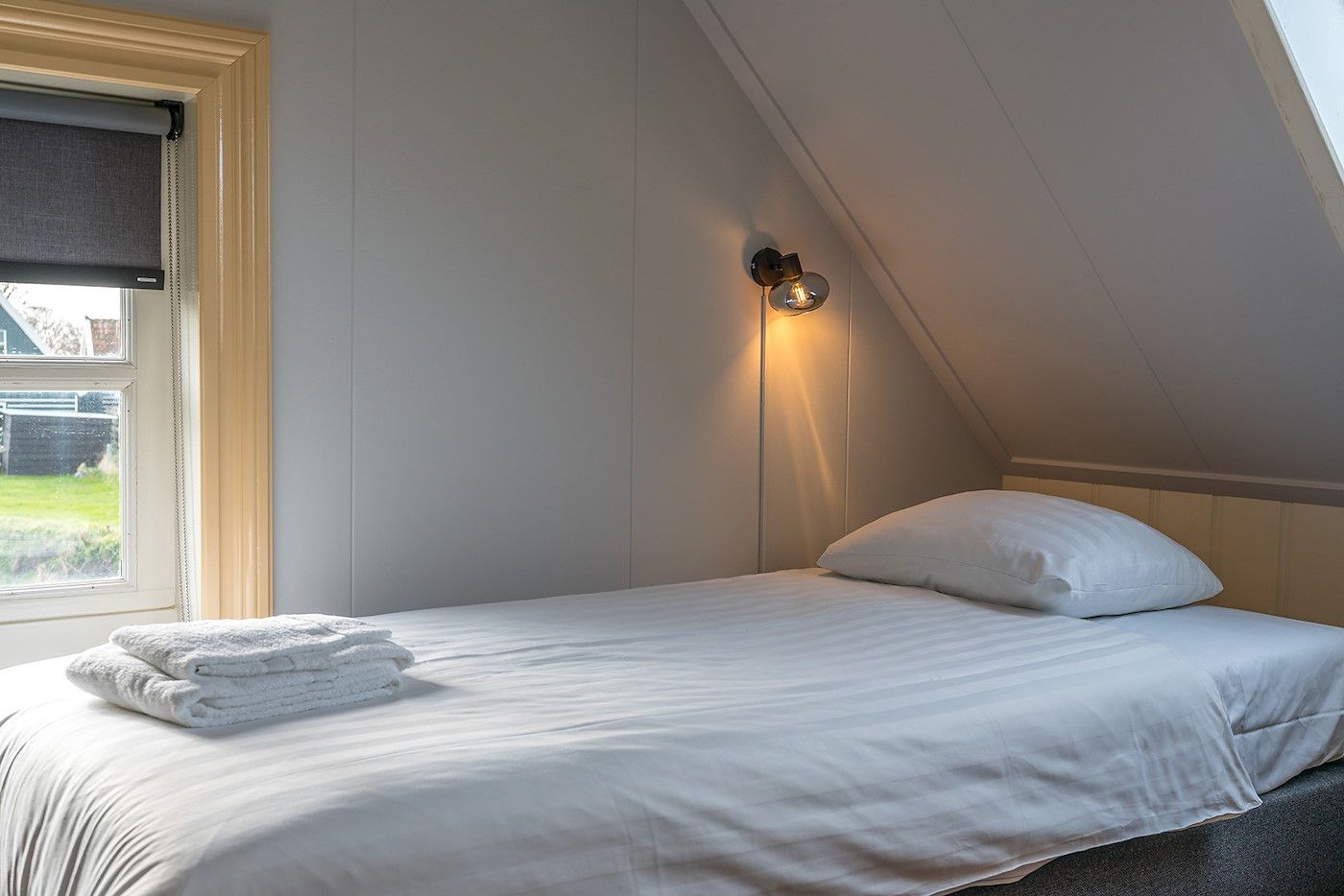 Gezellige slaapkamer in Gouden Rijder vakantiehuis, Oosterend, Texel, met uitzicht op de tuin.