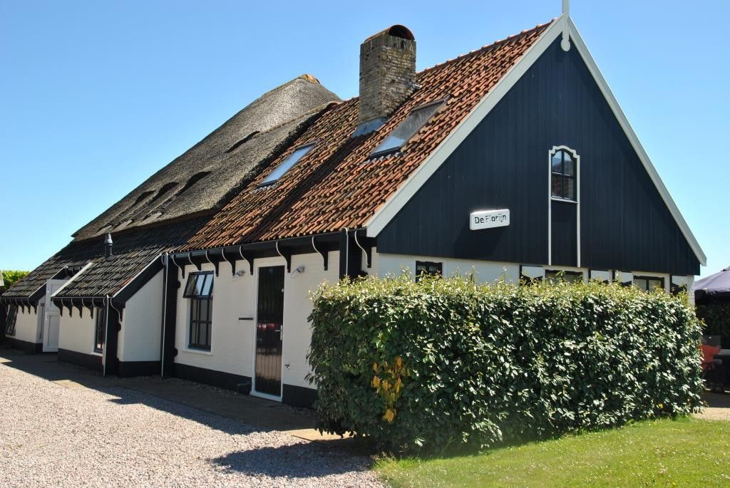 Achterzijde van Gouden Rijder vakantiehuis in Oosterend, Texel, met traditionele rieten dakbedekking.