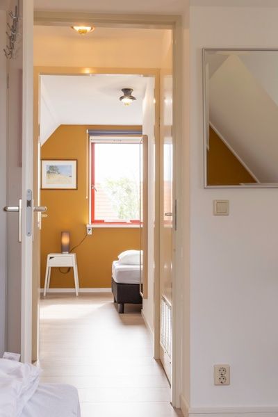Doorkijk naar slaapkamer in Type II+ - nr. 77 Goudvink vakantiehuis, Oosterend, Texel met warme kleuren.