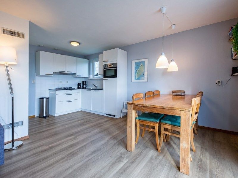 Eetruimte met houten tafel in vakantiehuis Type II - nr. 43 Stormvogel, Oosterend, Texel naast moderne keuken.