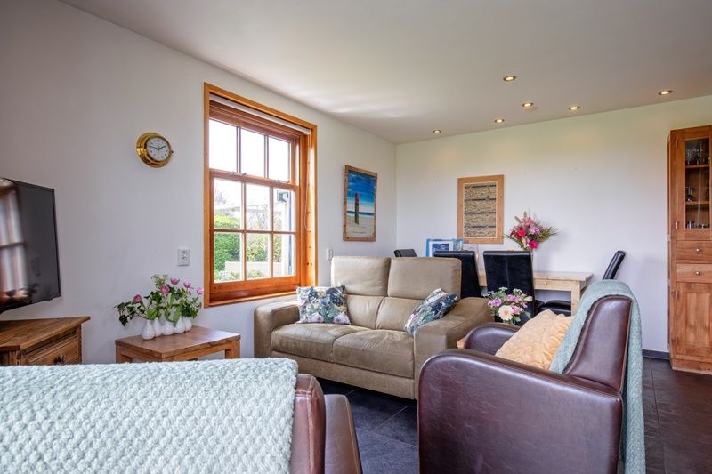 Lichte woonkamer van 't Raadsel in Oosterend Texel met moderne meubels en uitzicht op de tuin.