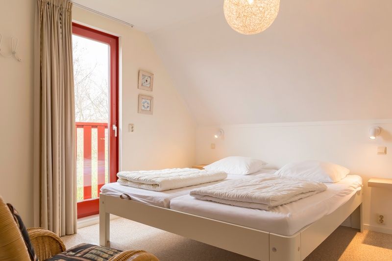 Schlafzimmer mit Balkon in Typ II - Nr. 81 Bachstelze, Oosterend, Texel, mit viel Tageslicht.