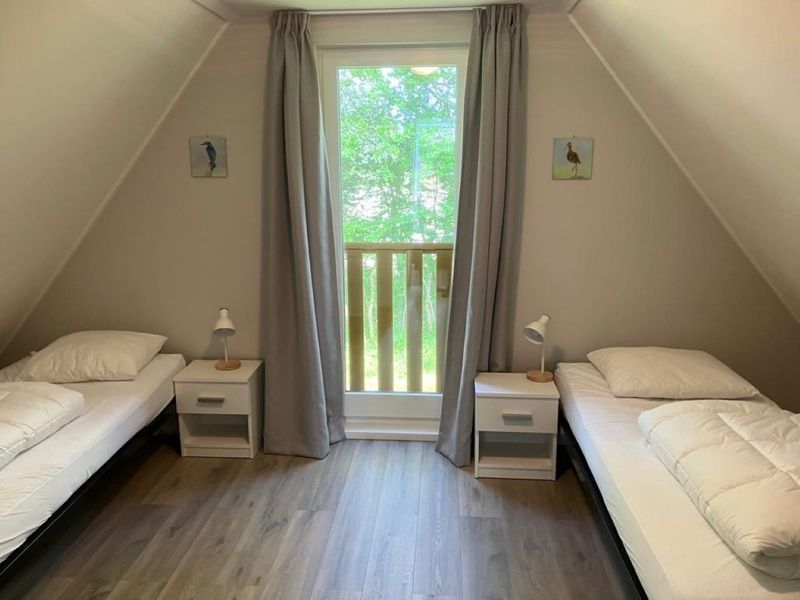 Second bedroom in Type I - No. 89 Lark, vacation home in Oosterend, Texel, with two single beds and views of greenery.