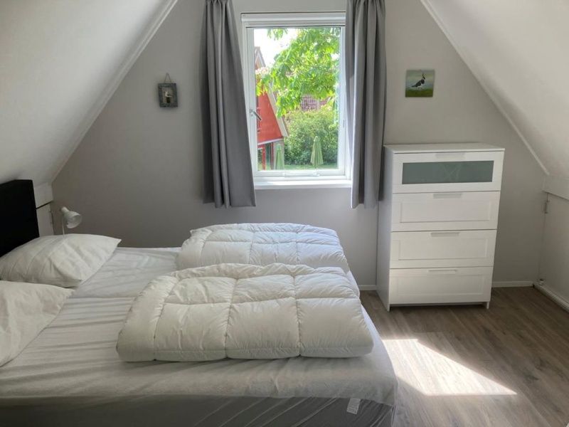Bright bedroom with double bed in Type I - No. 89 Lark, vacation home in Oosterend, Texel, overlooking garden.