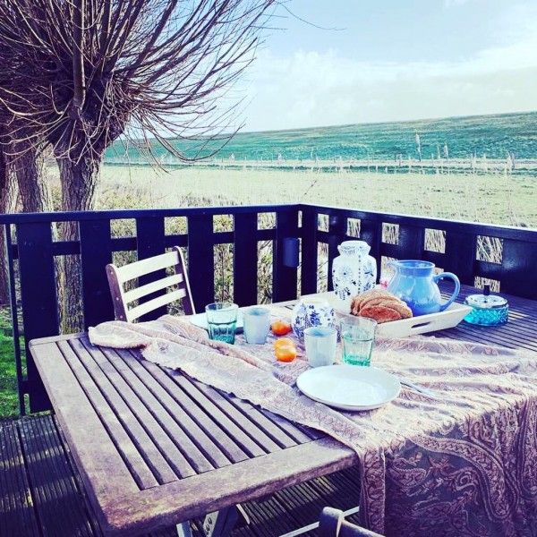 Ontbijt op het terras van 't Kaaps Huussie vakantiehuis in Oosterend, Texel met uitzicht over de velden.
