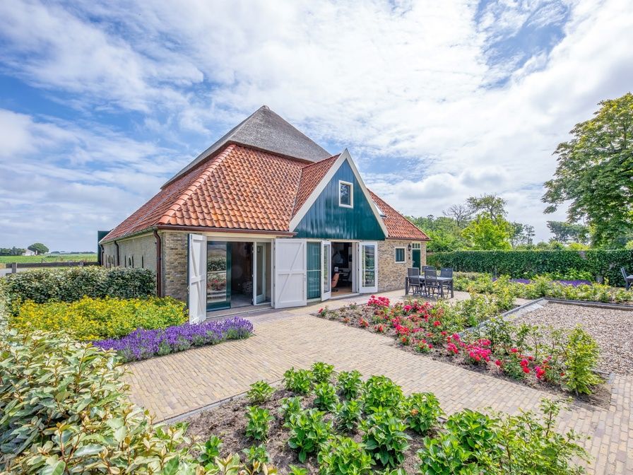 Charming exterior of Apartment C in Oudeschild, Texel, with colorful garden and terrace.