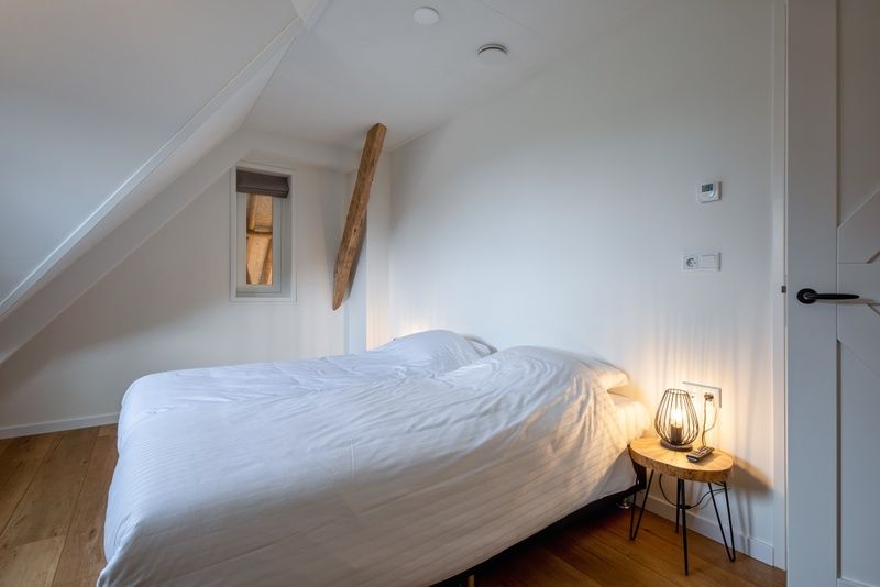 Cozy bedroom in Apartment C, Oudeschild, with wooden floor and mood lighting.