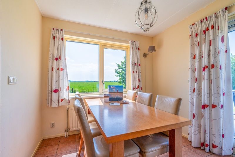 Dining room of The Five Star Holiday Home in South Eierland Texel with large windows and views of greenery.